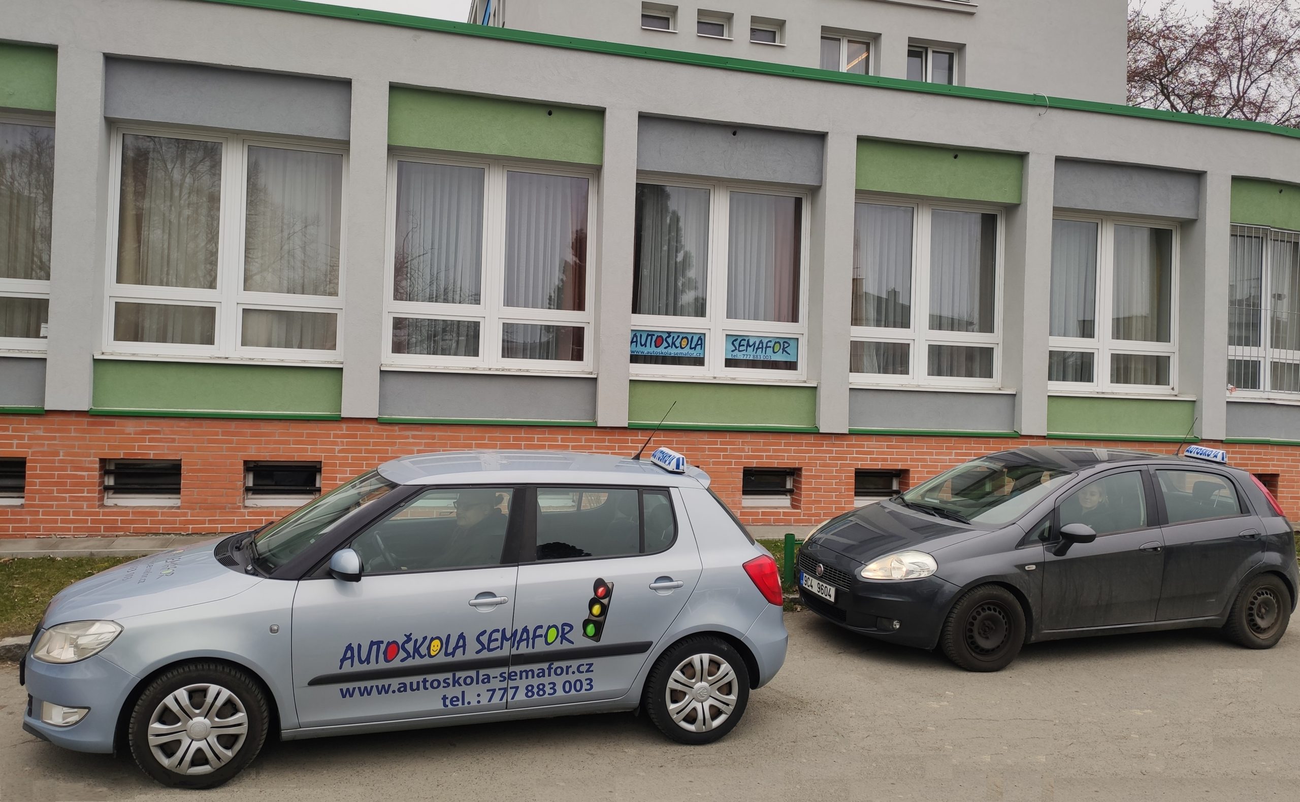 Výcviková vozidla Fábia a Fiat před učebnou autoškoly na kolejích Univerzity Karlovy Větrník